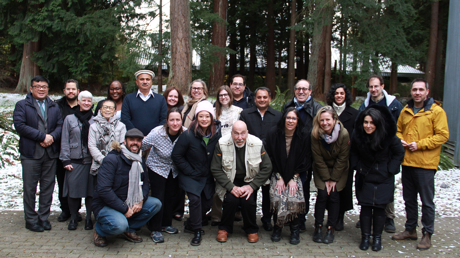 A group photo of people standing in front of trees