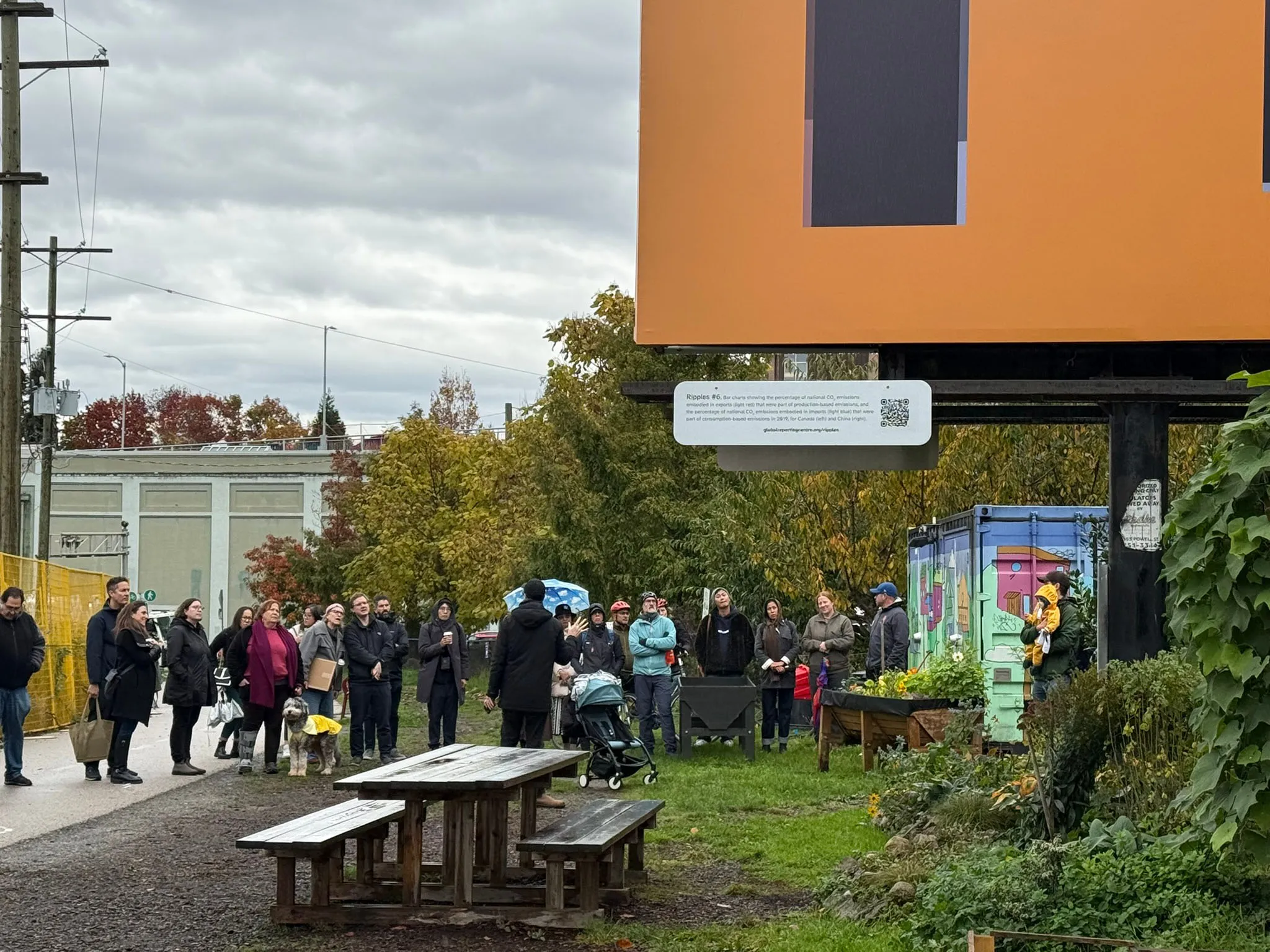 A man speaking to a group of people outdoors in a park-like setting about Ripples.