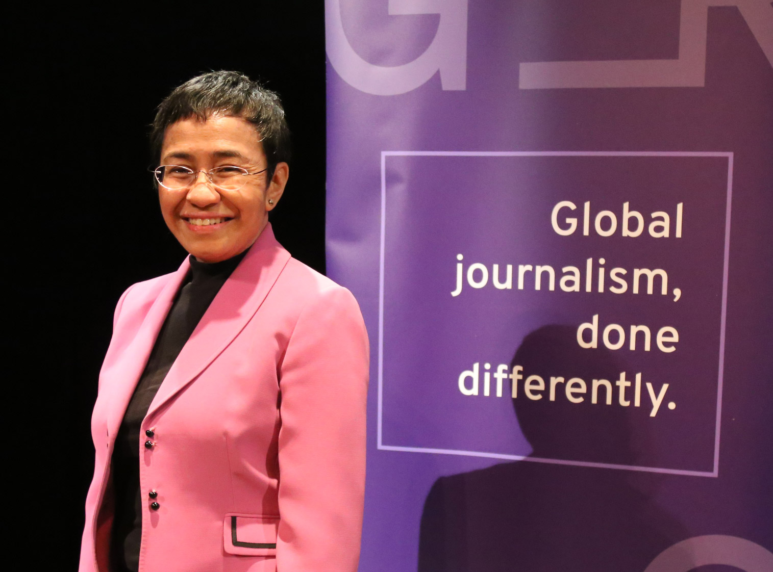 Maria Ressa standing in front of a banner