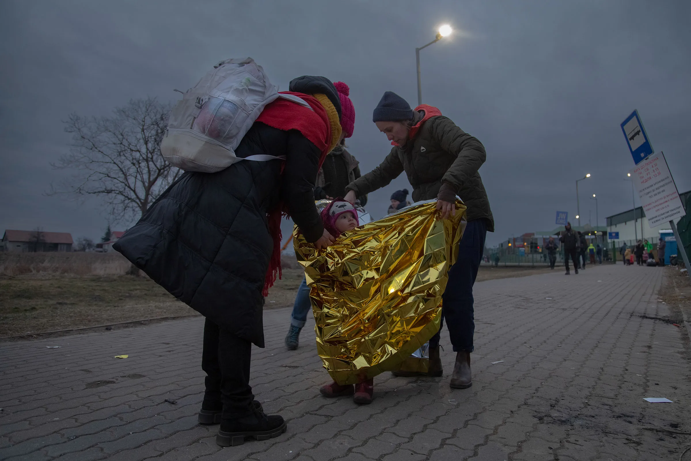 People wrapping a child in a reflective gold blanket